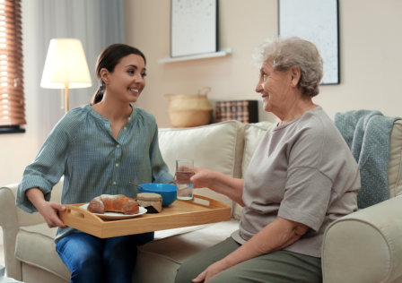 woman bringing food for the senior woman